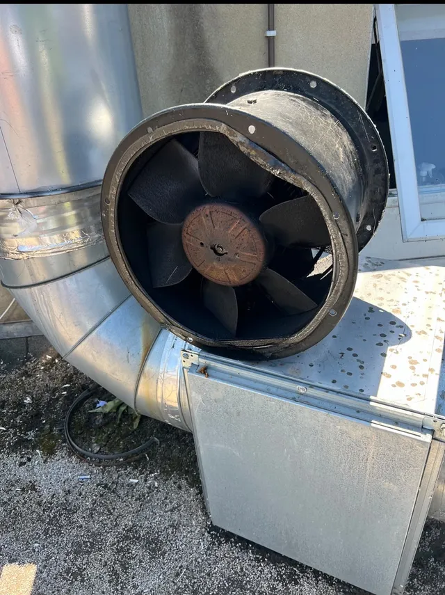Extractor fan on a roof with black grease on the blades